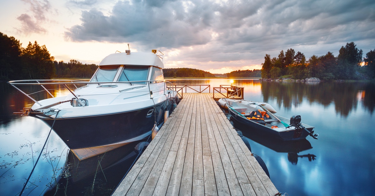 A small wooden pier with a platform at the end. There's a small cabin boat on one side and a fishing boat on the other.
