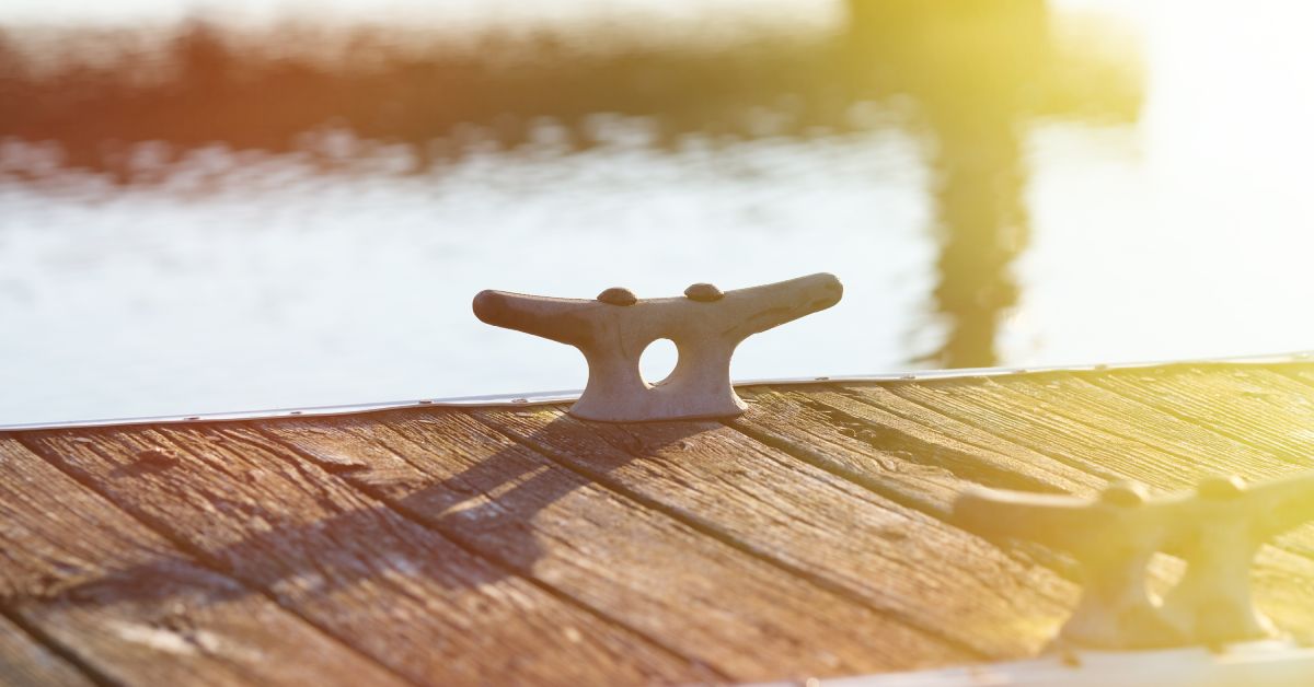 A close-up shot of metal cleats on a wooden dock with a metal frame; bright light is shinning in from the right side of the frame.