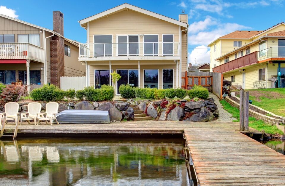 The backyard of a home with a long dock. The dock is clear along the walkway with chairs set up on one end.
