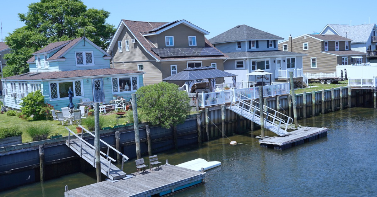 A row of large houses on a waterfront. Two of the homes have ramps and small docks attached to their backyard.